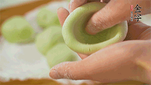 將均分的艾草面團(tuán)搓成圓，挖一個(gè)窩，放入餡心，再搓成圓。