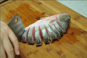 將鱸魚(yú)清洗干凈，從脊椎處切斷至腹部，腹部保留1cm左右不要切斷。