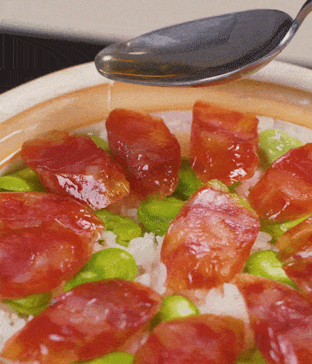 大米出現(xiàn)小孔時開蓋放香腸，往鍋邊淋入少許油，再燜煮8~10分鐘左右。